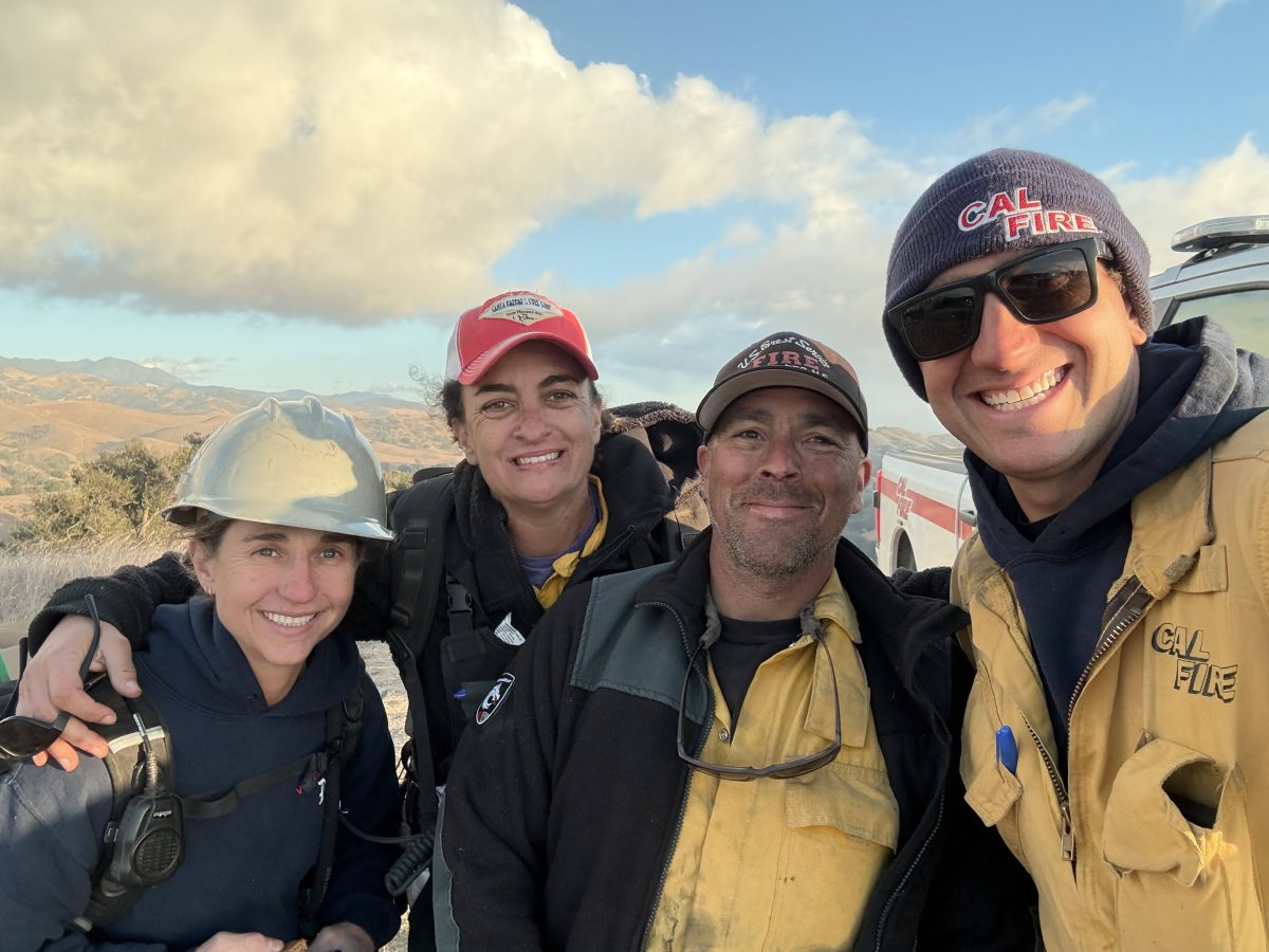 Four people in fire protective gear smiling